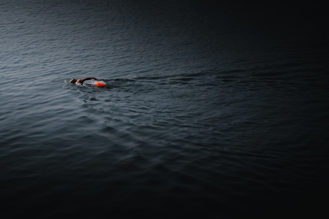 A person swims with a buoy in dark water.